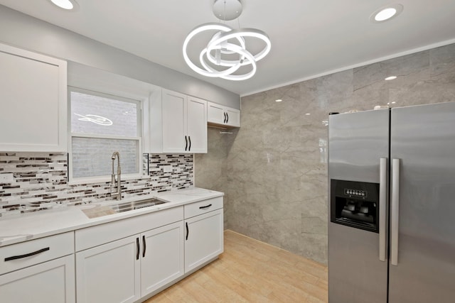 kitchen featuring sink, white cabinetry, an inviting chandelier, hanging light fixtures, and stainless steel fridge