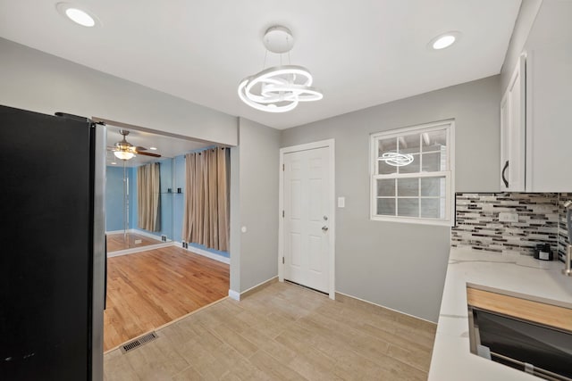 interior space featuring white cabinets, pendant lighting, stainless steel fridge, and light hardwood / wood-style flooring