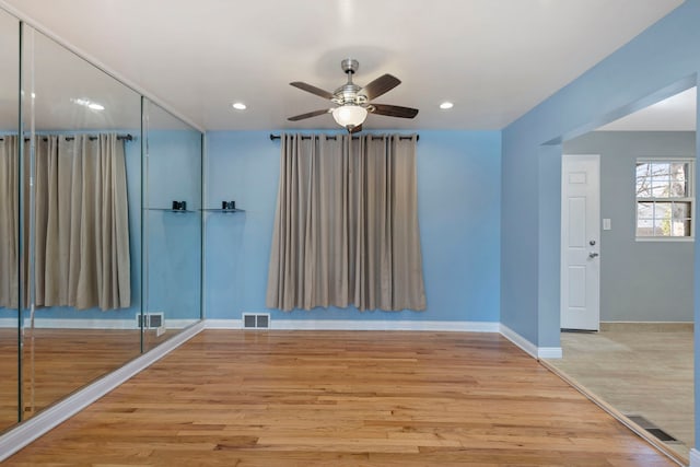 empty room with ceiling fan and light hardwood / wood-style floors