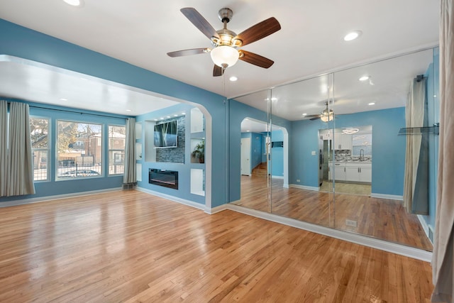 unfurnished living room with sink, ceiling fan, and light hardwood / wood-style flooring