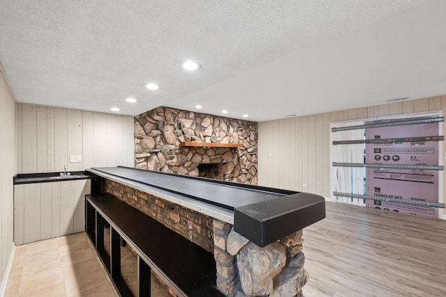 game room featuring a fireplace, a textured ceiling, and light wood-type flooring