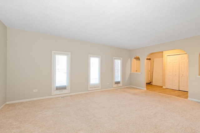 spare room with light carpet and a textured ceiling