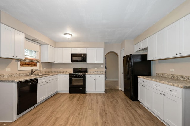 kitchen featuring sink, black appliances, light hardwood / wood-style flooring, light stone countertops, and white cabinets