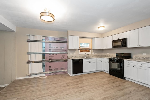 kitchen with sink, white cabinetry, light stone countertops, black appliances, and light hardwood / wood-style floors