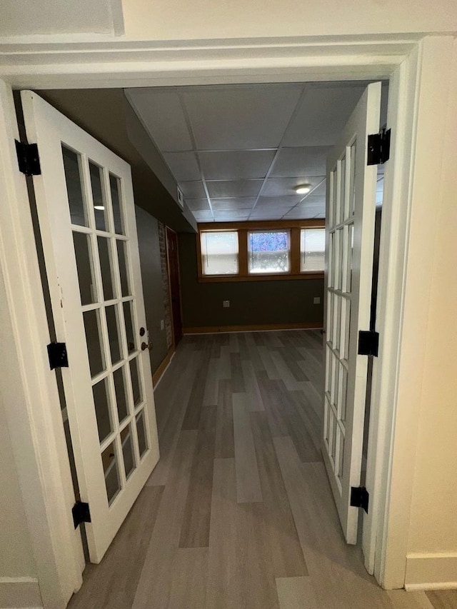 hallway featuring a drop ceiling, hardwood / wood-style flooring, and french doors