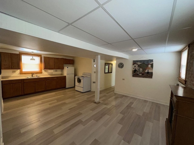 unfurnished living room with sink, a paneled ceiling, and light hardwood / wood-style flooring