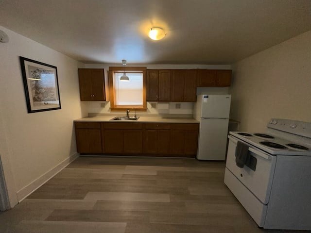 kitchen featuring sink, white appliances, and light wood-type flooring