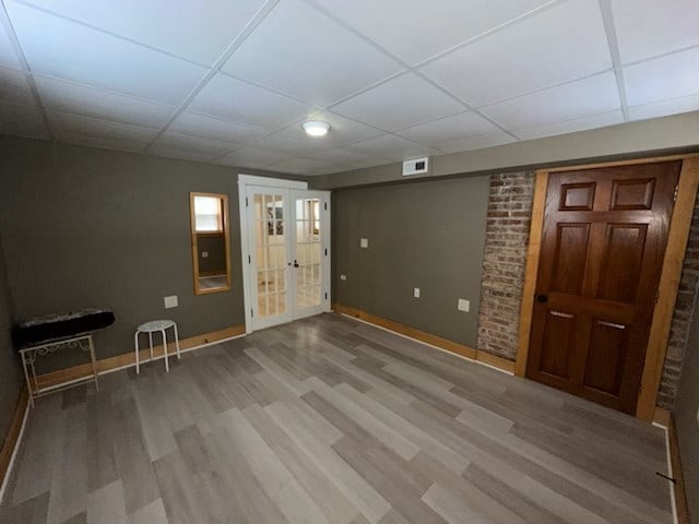 basement featuring a paneled ceiling, french doors, and wood-type flooring