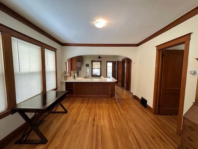 kitchen featuring crown molding, sink, light wood-type flooring, and kitchen peninsula