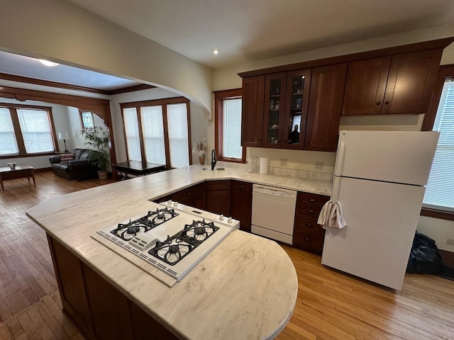 kitchen featuring white appliances, light hardwood / wood-style flooring, dark brown cabinets, and plenty of natural light