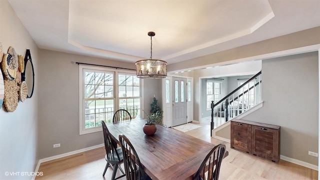 dining space with a wealth of natural light, a chandelier, and a tray ceiling