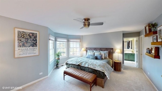 bedroom with ensuite bathroom, light colored carpet, and ceiling fan