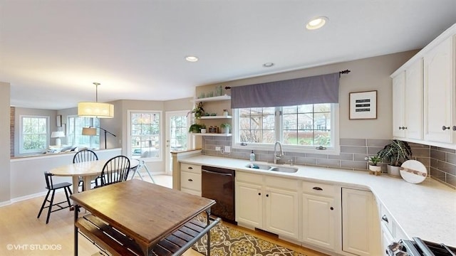 kitchen with pendant lighting, black dishwasher, sink, white cabinets, and decorative backsplash