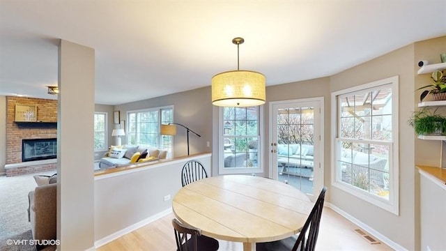 dining room featuring a brick fireplace and light hardwood / wood-style flooring