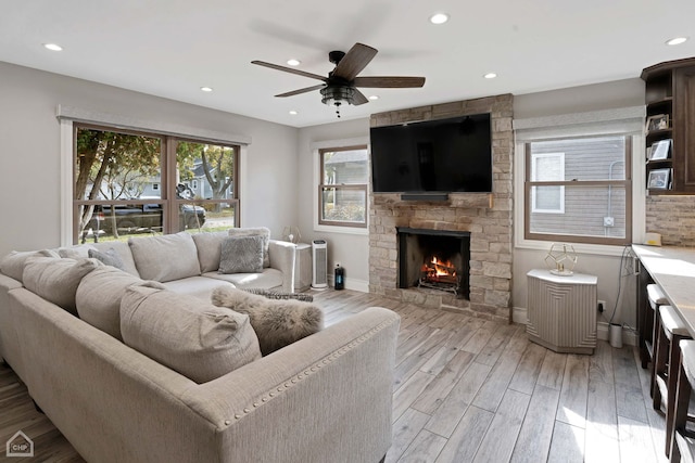 living room featuring a fireplace, light hardwood / wood-style floors, and ceiling fan