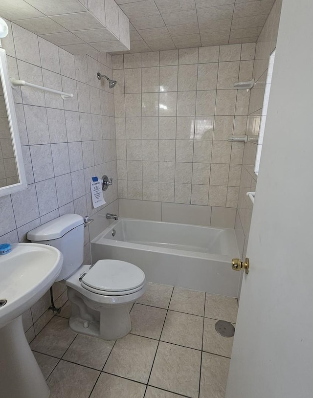 bathroom with toilet, tile patterned flooring, tile walls, and tiled shower / bath