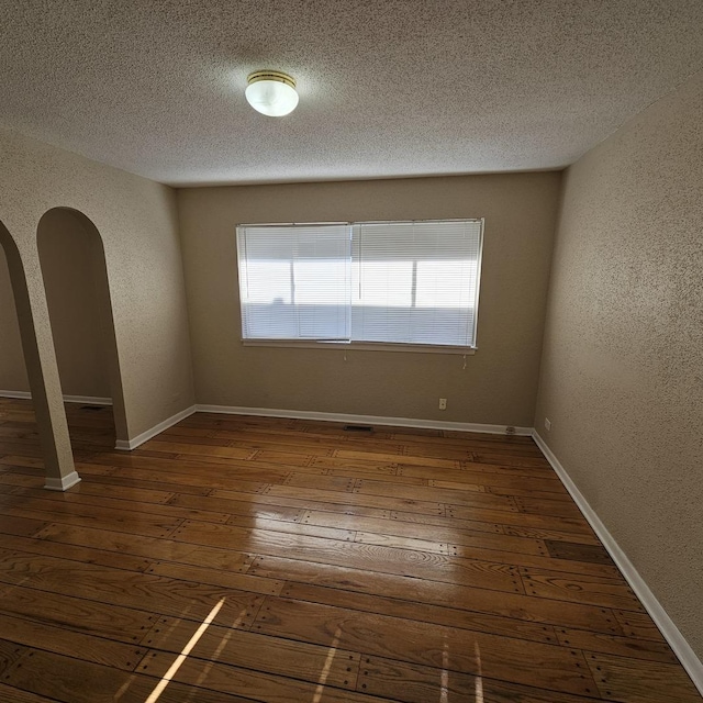 empty room featuring dark wood-type flooring and a textured ceiling