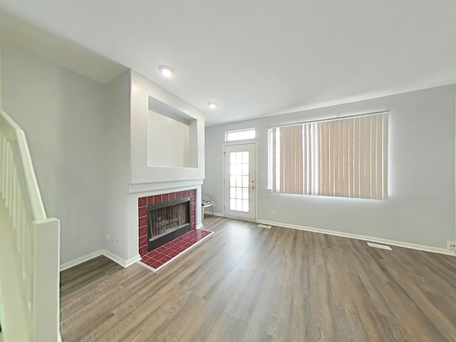 unfurnished living room featuring a brick fireplace and hardwood / wood-style flooring