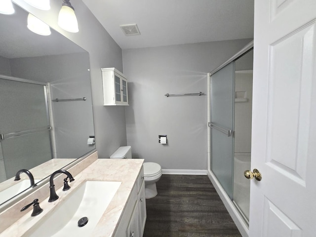 bathroom with an enclosed shower, vanity, wood-type flooring, and toilet