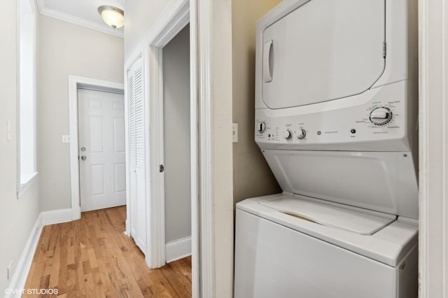 clothes washing area featuring ornamental molding, stacked washer / dryer, and light hardwood / wood-style flooring