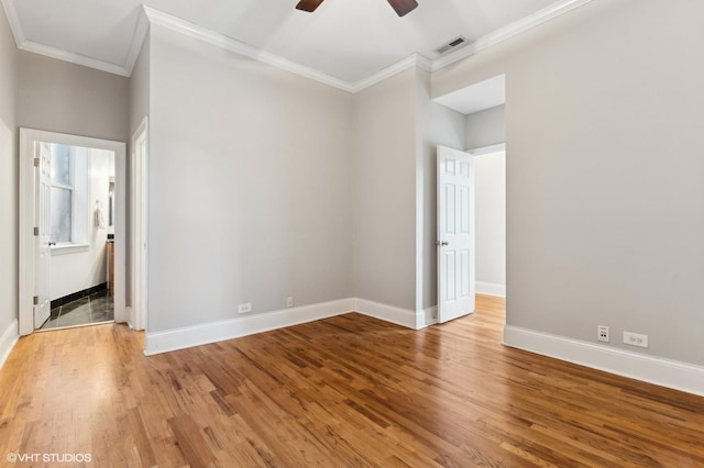 unfurnished bedroom featuring hardwood / wood-style flooring, crown molding, ensuite bathroom, and ceiling fan