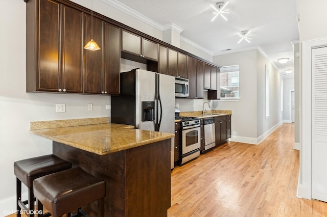 kitchen featuring crown molding, light stone counters, decorative light fixtures, appliances with stainless steel finishes, and kitchen peninsula