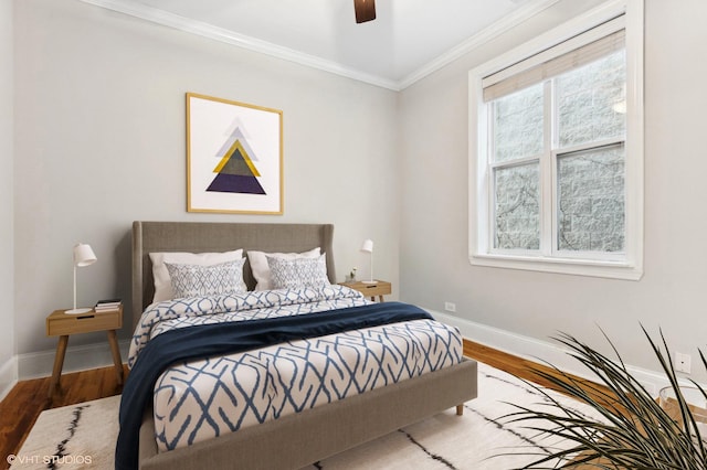 bedroom featuring hardwood / wood-style flooring, ornamental molding, and ceiling fan