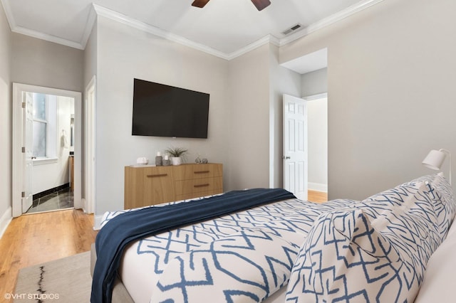 bedroom featuring ornamental molding, hardwood / wood-style floors, ceiling fan, and ensuite bath