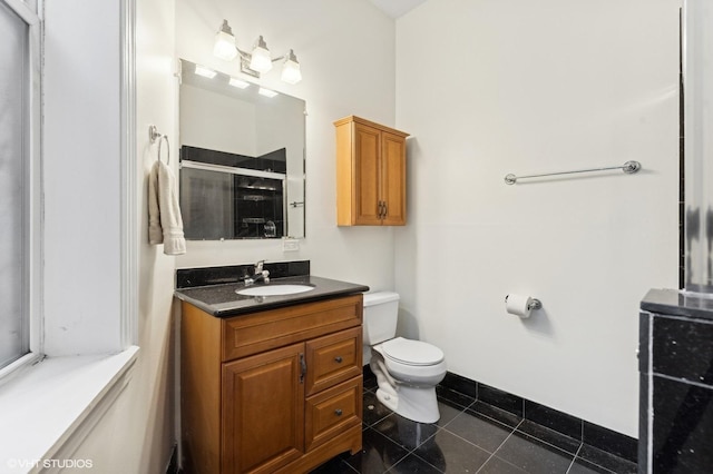 bathroom with vanity, a shower with shower door, tile patterned floors, and toilet