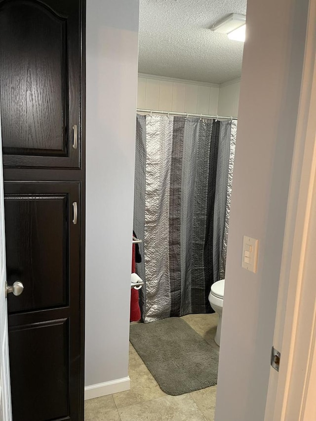 bathroom with a textured ceiling, toilet, and walk in shower