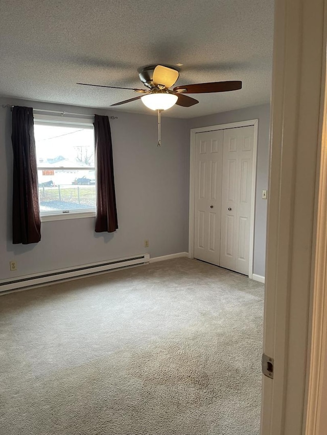 unfurnished bedroom featuring a textured ceiling, carpet floors, a baseboard heating unit, a closet, and ceiling fan