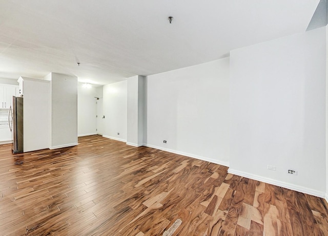 basement featuring wood-type flooring and stainless steel fridge