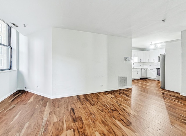 unfurnished living room featuring sink and light hardwood / wood-style floors