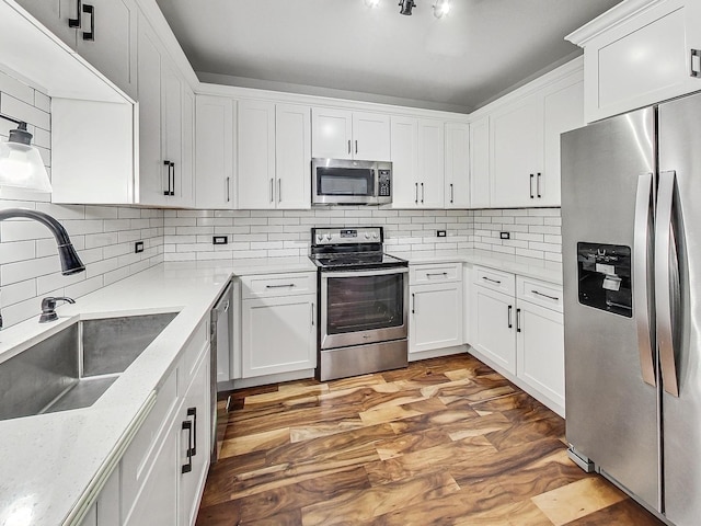 kitchen featuring sink, white cabinets, decorative backsplash, stainless steel appliances, and light stone countertops