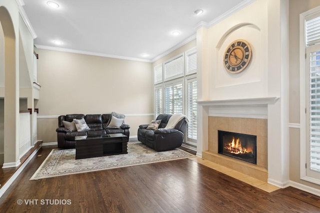 living room with dark wood-type flooring, a fireplace, and ornamental molding