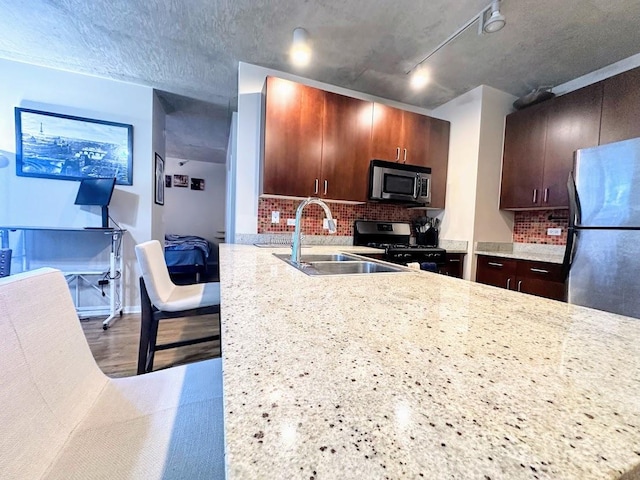 kitchen featuring light stone countertops, tasteful backsplash, sink, kitchen peninsula, and stainless steel appliances