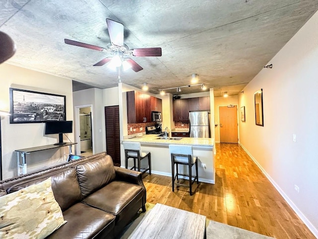 living room featuring sink, light hardwood / wood-style floors, ceiling fan, and track lighting