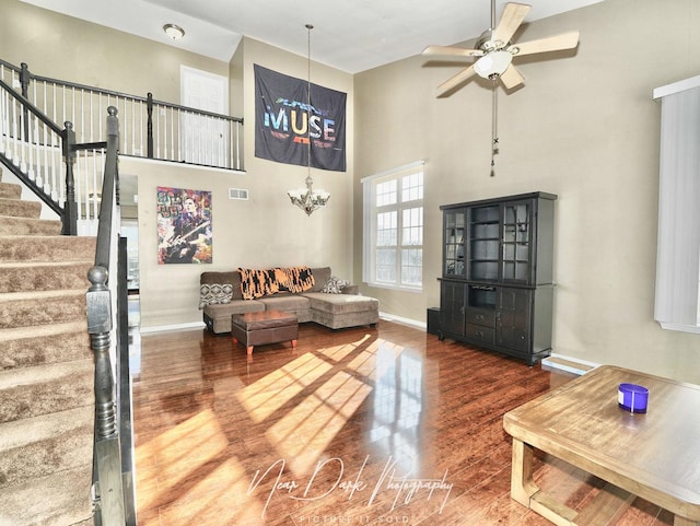 living room with ceiling fan, hardwood / wood-style flooring, and a towering ceiling