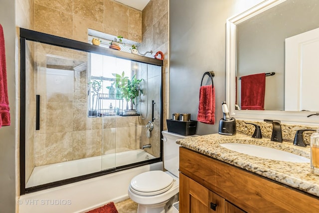 full bathroom featuring vanity, bath / shower combo with glass door, and toilet