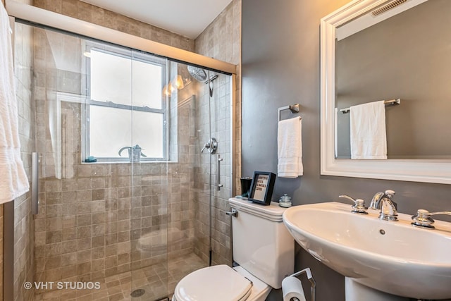 bathroom featuring walk in shower, toilet, and sink