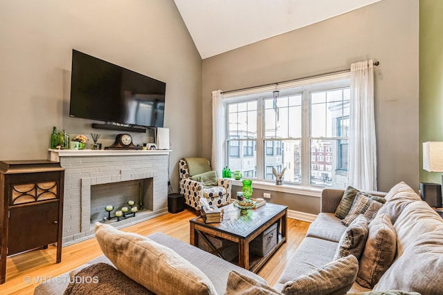 living room with vaulted ceiling, a fireplace, and light hardwood / wood-style flooring