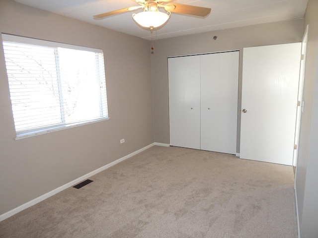 unfurnished bedroom featuring light carpet, a closet, and ceiling fan