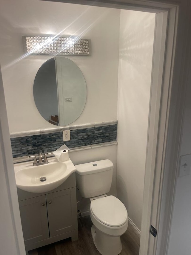 bathroom with wood-type flooring, backsplash, toilet, and vanity