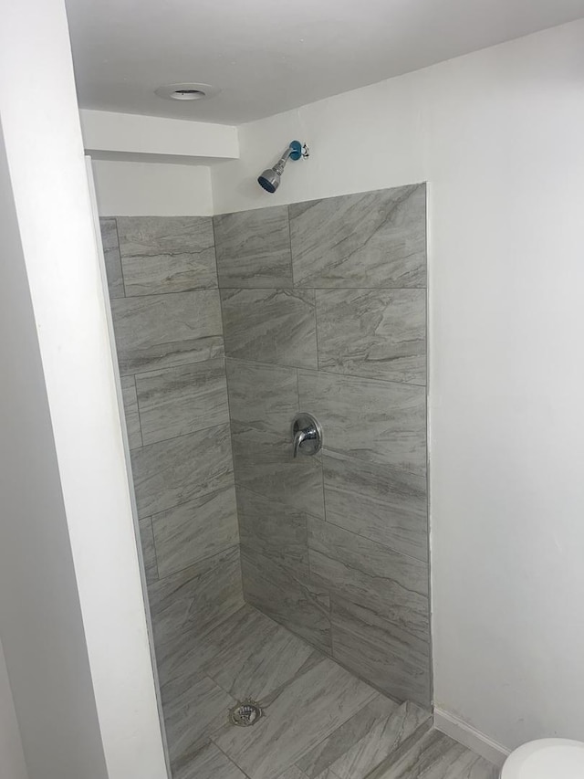 bathroom featuring tiled shower and toilet