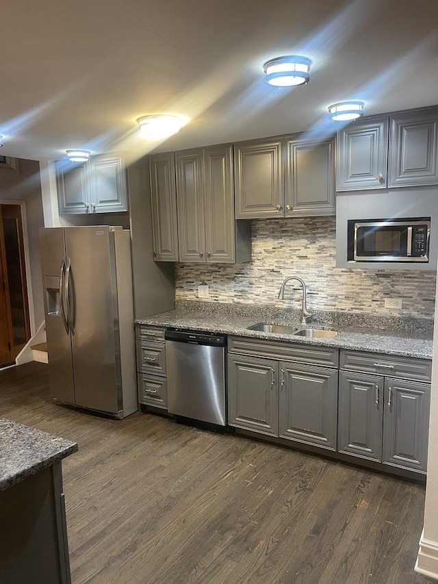 kitchen featuring sink, light stone counters, dark hardwood / wood-style flooring, and appliances with stainless steel finishes