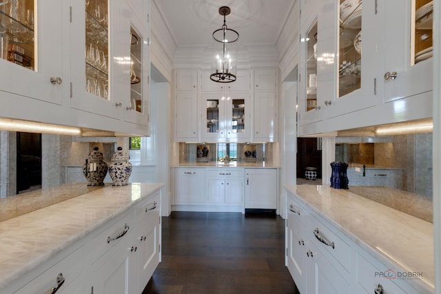 bar with light stone countertops, white cabinets, and decorative light fixtures