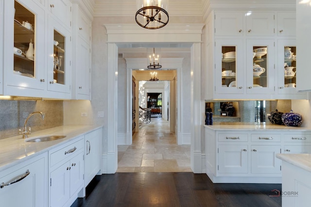 bar with pendant lighting, sink, light stone counters, and white cabinets