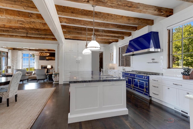 kitchen featuring blue cabinetry, wall chimney exhaust hood, sink, white cabinetry, and hanging light fixtures