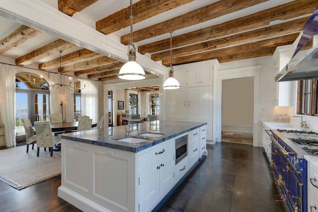 kitchen with white cabinetry, sink, decorative light fixtures, and an island with sink