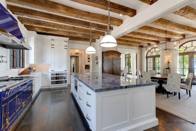 kitchen with blue cabinets, hanging light fixtures, a kitchen island, dark stone counters, and white cabinets